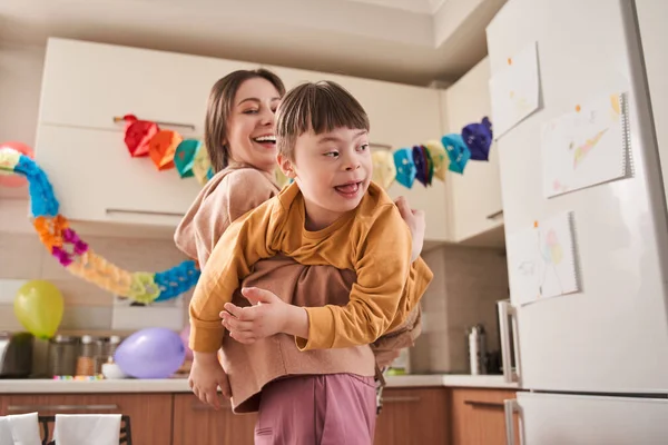 私の現役の少年 若い魅力的な母親が一緒に素晴らしい時間を過ごしながら 台所で遺伝障害を持つ彼女の息子と遊んでいます ストックフォト — ストック写真