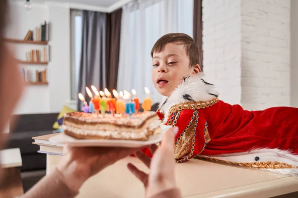 집에서 축하하면서 증후군 아들에게 촛불을 케이크를 가져온 어머니의 띄었다 — 스톡 사진
