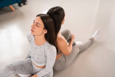 Spor giysili kızların arka arkaya sırtüstü uzandığı yüksek açılı bir manzara. Spor rutini ve arkadaşlık kavramı. Stok fotoğrafı