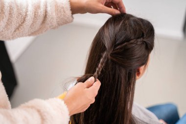 Kadın ellerinin, esmer en iyi arkadaşının iç mekândaki saçlarını örerken çekilmiş görüntüsü. Stok fotoğrafı