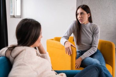 Sakin kadınlar kanepede dinleniyor ve evlerinde birbirleriyle konuşuyorlar. Genç kızlar sohbet edip komik şeylerden bahsediyorlar. Evdeki kanepede dedikodu yapıp gülüyorlar.