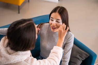 Evcil güzellik rutini. Göz altına maske takarak eğlenen güzel kızların yüksek açılı görüntüsü. Stok fotoğrafı