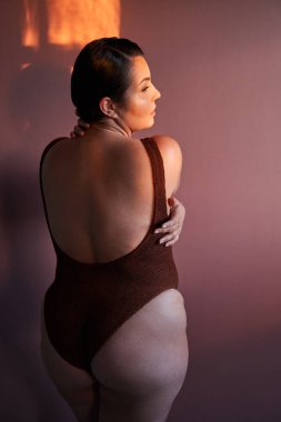 Kendini sev ve kucakla. Pembe stüdyo arka planında çıplak omuzlarıyla poz veren, mükemmel ciltli pozitif siyah kadın.