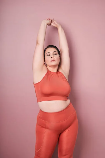 Уверенная Женщина Спортивной Одежде Поднимает Руки Позирует Над Розовой Стеной — стоковое фото