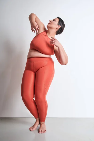 stock image Vertical view of the plus size woman posing alone at studio. Body positive female smiling and standing isolated over white studio background