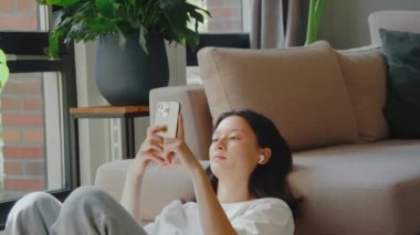 Akıllı telefonunu tutan ve selfie çekerken kameraya poz veren ya da evdeki video konuşmalarıyla konuşan bir kadın. Teknoloji ve insanlar kavramı