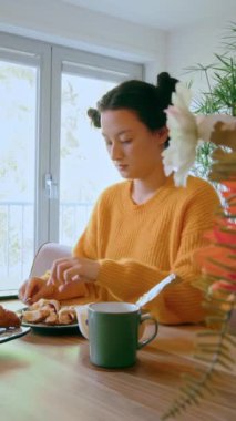 Şık esmer kız mutfakta oturuyor ve sabahları portakal suyuyla kruvasan yiyor. Halk yaşam tarzı konsepti