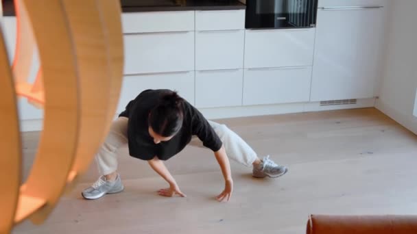 木製の床に立っている間に広がるアジアの女性の完全な長さのビュー ブルネット女性行う彼女の練習で彼女の家 — ストック動画