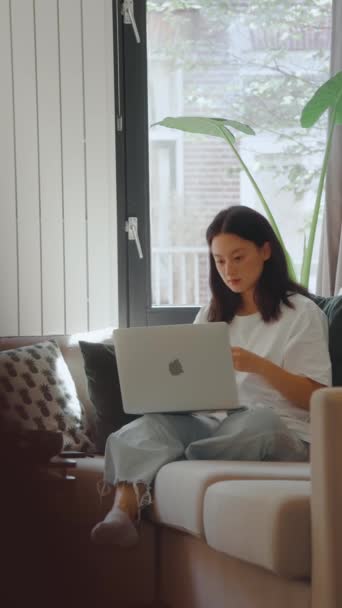 Вертикальний Вигляд Усміхненої Дівчини Яка Носить Навушники Відкриває Ноутбук Сидячи — стокове відео