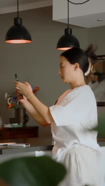 Akıllı Telefon Tutan Asyalı Kızın Dikey Görüntüsü Aydınlık Bir Mutfakta — Stok video