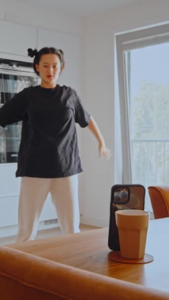 버뮤다흰 스마트폰 앞에서 유리를 라이브 스트림을 만들고 주방에서 춤추는 아시아 — 비디오