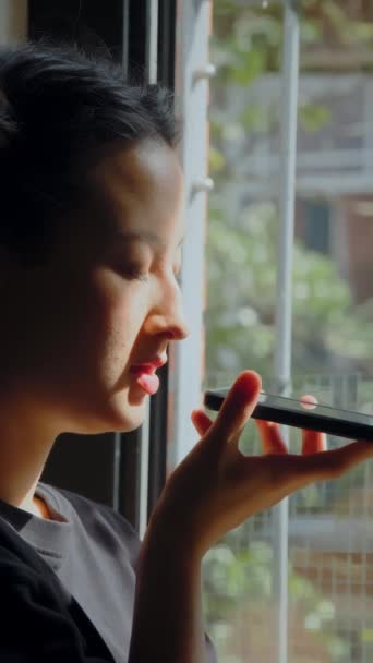 居心地の良い枕に座っている深刻なアジアの少女の垂直方向のビューと友人に音声メッセージを記録します 国内のライフスタイルと技術コンセプト — ストック動画