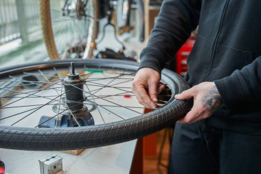 Atölyede erkek bisikletçi kontrol tekeri görüntüsü konuşuldu. Bisiklet servisi, tamir ve geliştirme. Araç gereç ve ekipman ile garaj içi