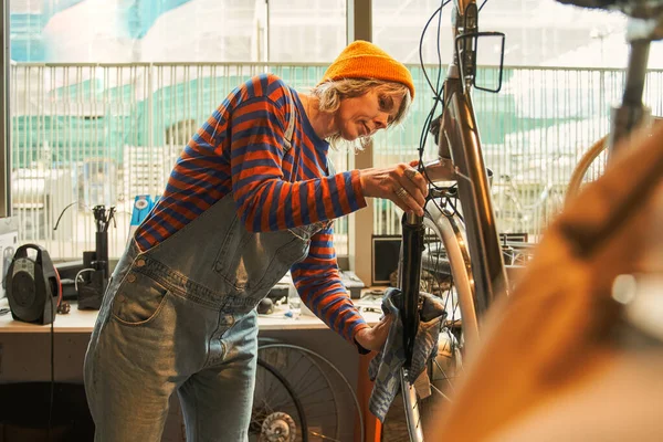 Kobieta Kombinezonie Pracuje Warsztacie Rowerowym Poważna Pani Stojąca Pobliżu Roweru — Zdjęcie stockowe