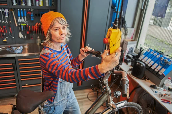 Perseverante Maestro Femenino Reparando Bicicleta Montaña Mientras Mira Panel Herramientas — Foto de Stock