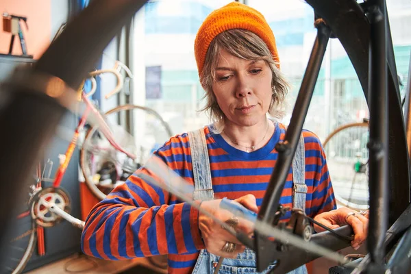 Σοβαρή Καυκάσια Γυναίκα Εργαζόμενος Επισκευή Τροχό Ποδηλάτου Ενώ Στέκεται Στο — Φωτογραφία Αρχείου