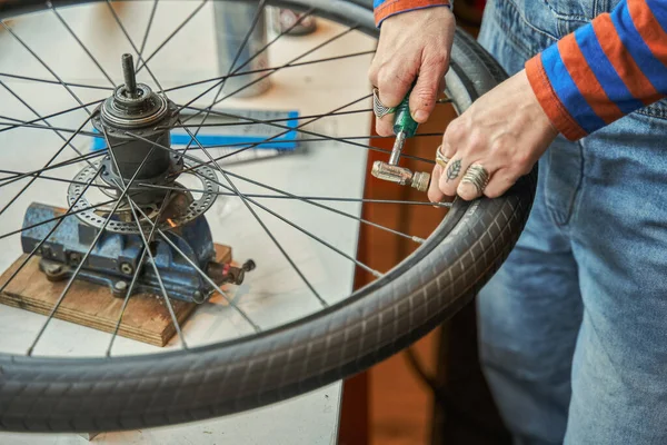 stock image Close up view of woman mechanic hands working in bicycle repair shop. Unknown lady repairing bike using special tools. Occupation concept