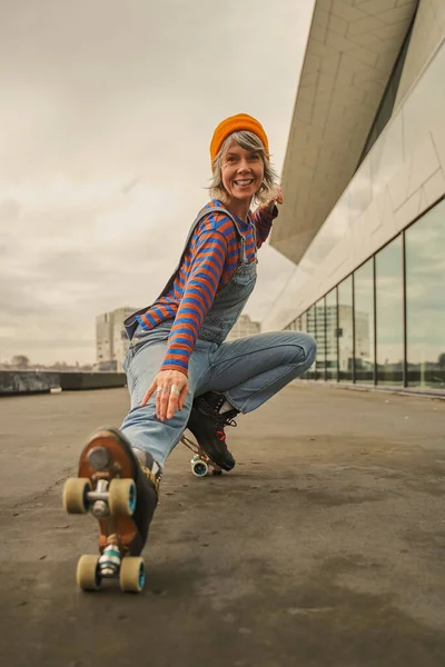 在城市街道上乘坐滑冰鞋的积极女子的垂直视图 现代女子在溜冰鞋上摆姿势 — 图库照片