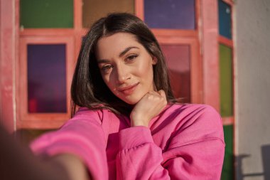 Güzel esmer kız arka planda canlı bir duvarla yaz caddesinde selfie çekiyor. Halk yaşam tarzı konsepti