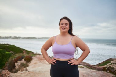 Kumsalda tek başına yürürken kameraya bakıp deniz doğasının tadını çıkaran neşeli bir kadın. Halk yaşam tarzı konsepti