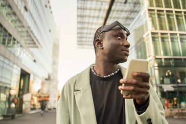 Cep telefonu tutan ve şehirde yürürken gözlerini kaçıran çok ırklı rahat bir adam. Yakışıklı adam tek başına dinleniyor.