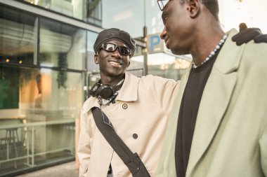 Sıcak sonbahar gününün tadını çıkarırken cam mimarisinin yanında yürüyen iki erkek arkadaş. Halk yaşam tarzı konsepti