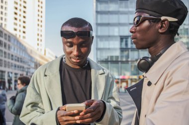 İki çok ırklı kardeş şık kıyafetler giyip yürürken akıllı telefon tutuyorlar. Arkadaşlık kavramı
