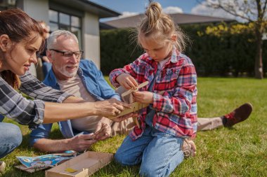 Küçük kız çimenlikte birlikte otururken annesi ve büyükbabasıyla vakit geçiriyor. Halk yaşam tarzı konsepti
