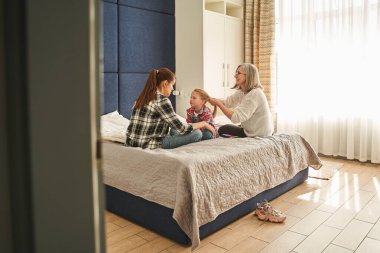 Üç kuşak. Yaşlı kadın kızıyla konuşurken küçük kızın saçını tarıyor. Aile ilişkileri kavramı