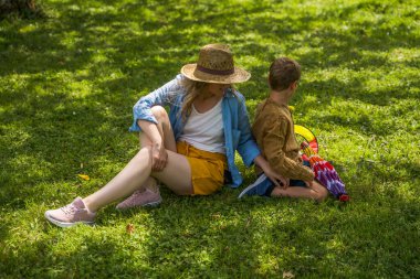 Açık havada mutlu bir aile kavramı. Sevgili annesi ve küçük oğlu yeşil çimlerde tatillerde birlikte aktiviteler yapıyorlar.
