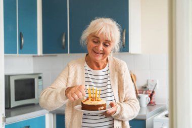 Kutlama pastasında mum yakan yaşlı bir kadın, sevinçlerini dile getiriyor..