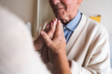 Birbirlerini sımsıkı tutan yaşlı bir çiftin ellerine yakın çekim. Yaşlılıkta destek kavramı.