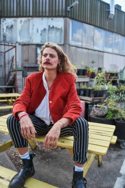 Uzun saçlı, modaya uygun bir adam sokakta poz verip gözlerini kaçırıyor. Cinsiyet eşitliği kavramı