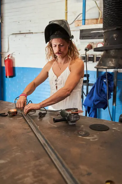Professional feminine carpenter is enjoying his job. Longhaired man with moustaches posing at his workplace. Stock photo