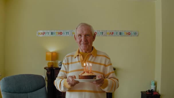 老人拿着生日蛋糕 吹着蜡烛 上了年纪的夫妇在家里举行生日聚会 — 图库视频影像