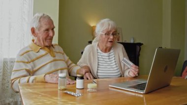 Üst düzey bir çift, doktorla konuşurken oturma odasında bilgisayar kullanıyor.