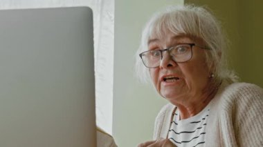 Kıdemli kadın internette doktorla konuşuyor. Yaşlı kadın hasta ve doktor görüntülü telefonda dizüstü bilgisayarla görüşüyor. Tıbbi sağlık hizmetleri sağlık kontrolü
