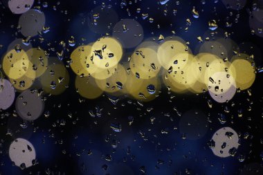 Karanlıkta parlayan ışıklar ve parıldayan su damlaları.