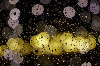 Karanlıkta parlayan ışıklar ve parıldayan su damlaları.