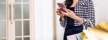 Modayla ilgili mutlu kadın portresi rahatla ve alışveriş zamanının tadını çıkar yaz yürüyüşü ve bir şeyler satın almak için renkli bir çanta al mağazada akıllı telefon kullan.