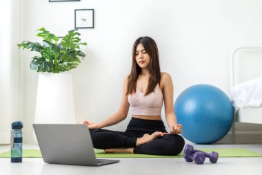 Portre sporu spor, spor kıyafetleri içinde ince kadın, rahatlama ve yoga yapan kız, yatak odasında dizüstü bilgisayarla spor yapıyor. Diyet konsepti. Fitness ve sağlıklı.