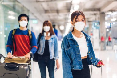 Coronavirus yüzünden karantinada olan mutlu genç bir arkadaş koruyucu maske takıyor. Uluslararası terminal havaalanında uzun bir tatil uçuşundan önce pasaport ve bilet tutuyor.