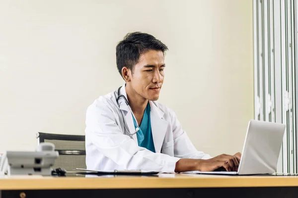 Asian man doctor wearing uniform with stethoscope working with laptop computer in hospital.healthcare and medicine