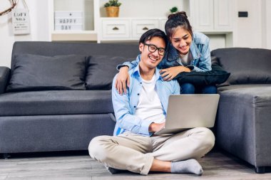 Genç Asyalı çift dizüstü bilgisayarla rahatlıyor ve video konferansında online sohbet ediyorlar. Yaratıcı iş çifti strateji analizi ve evde beyin fırtınası planlıyor.