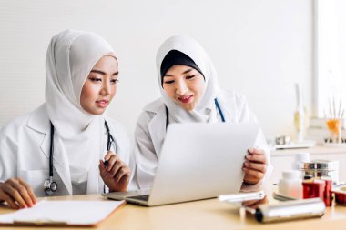 İki müslüman Asyalı kadın doktor pano ve tablet bilgisayarla çalışıyor. Hasta hastaları kontrol ediyorlar. Sağlık ve tıp.