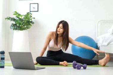 Portre sporu spor, spor kıyafetleri içinde ince kadın, rahatlama ve yoga yapan kız, yatak odasında dizüstü bilgisayarla spor yapıyor. Diyet konsepti. Fitness ve sağlıklı.