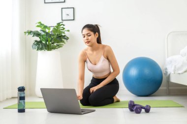 Portre sporu spor, spor kıyafetleri içinde ince kadın, rahatlama ve yoga yapan kız, yatak odasında dizüstü bilgisayarla spor yapıyor. Diyet konsepti. Fitness ve sağlıklı.