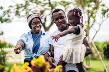 Mutlu aşk portresi Afro-Amerikan aile Afrikalı baba ve anne ve küçük Afrikalı kız çocuk gülümseyerek ve evde iyi vakit geçirerek eğleniyorlar.