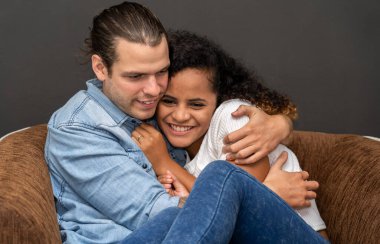 Romantik, genç, mutlu, beyaz erkek ve Afro-Amerikan kadın gülümseyip siyah arka planda sevgililer gününde kucaklaşıyorlar.