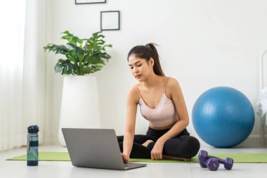 Portre sporu spor, spor kıyafetleri içinde ince kadın, rahatlama ve yoga yapan kız, yatak odasında dizüstü bilgisayarla spor yapıyor. Diyet konsepti. Fitness ve sağlıklı.